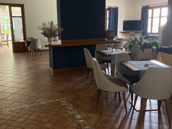 Area con tavoli e sedie, separata da un muro blu.