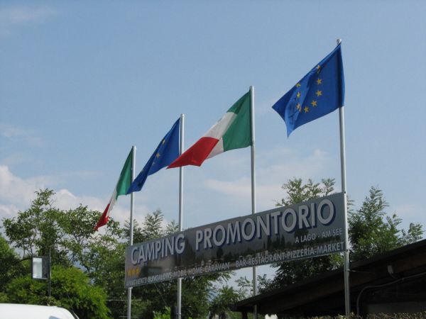 Insegna di un campeggio con bandiere europea e italiana.