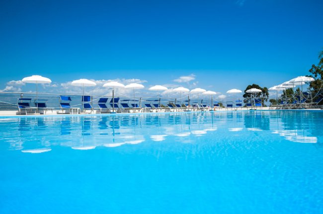 Vista della piscina con ombrelloni bianchi.