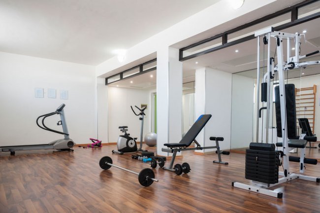 Una palestra con attrezzi e pavimento in legno.
