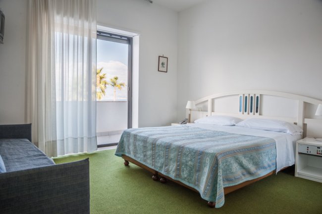 Camera da letto con letto matrimoniale e balcone vista mare.