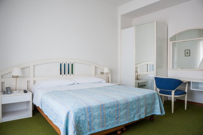 Camera da letto luminosa con letto matrimoniale e sedia blu.