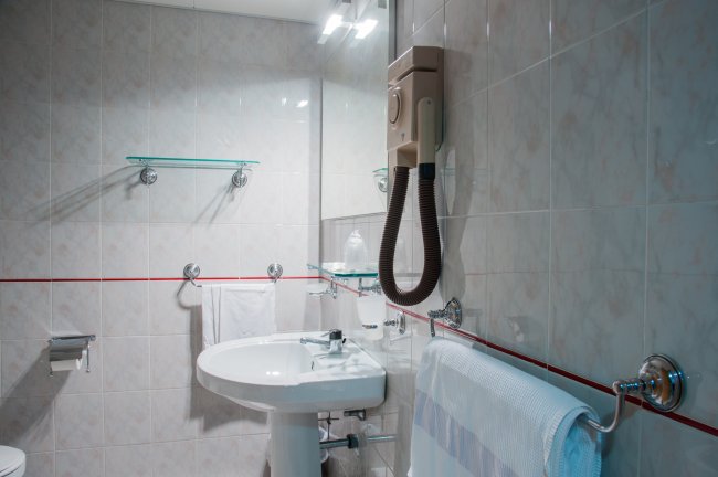Bagno bianco con lavandino e asciugacapelli.