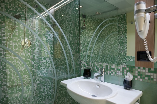 Bagno moderno con piastrelle verdi e doccia in vetro.