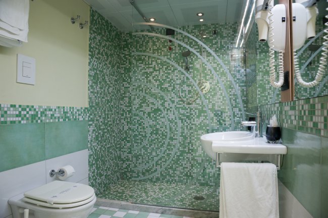 Bagno con piastrelle verdi, lavandino e wc.