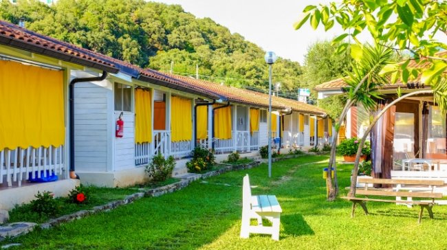 Una fila di bungalow con tende gialle su un prato verde.