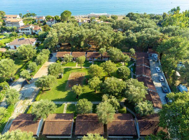 Vista aerea di villette tra alberi vicino al mare.