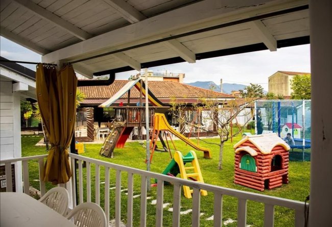 Un'area giochi all'aperto con scivoli, altalene e una casetta su un prato.