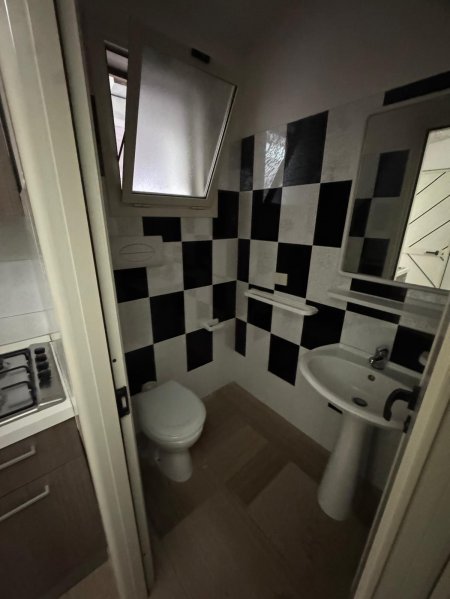 Bagno con piastrelle bianche e nere, lavabo e finestra.