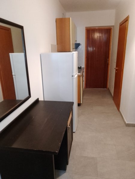 Corridoio con frigorifero, tavolo e specchio, porta in fondo.