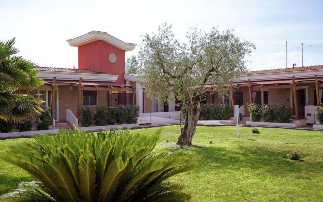 Giardino con edificio basso e alberi.