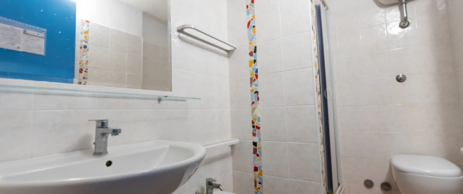 Bagno con lavabo, specchio, doccia e decorazioni colorate.