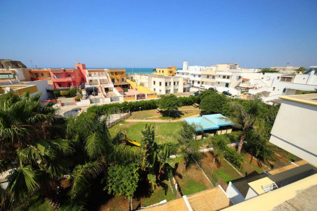Vista di un quartiere colorato con giardini e mare sullo sfondo.