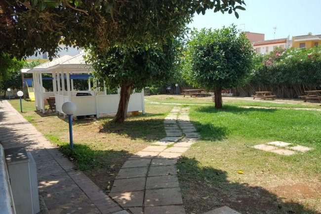 Un giardino con sentiero, gazebo e alberi in un'area esterna.