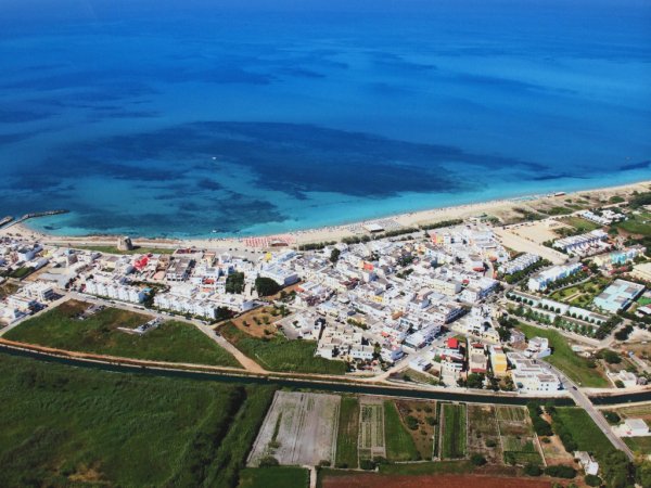 Vista aerea di una città costiera con spiagge e mare blu.