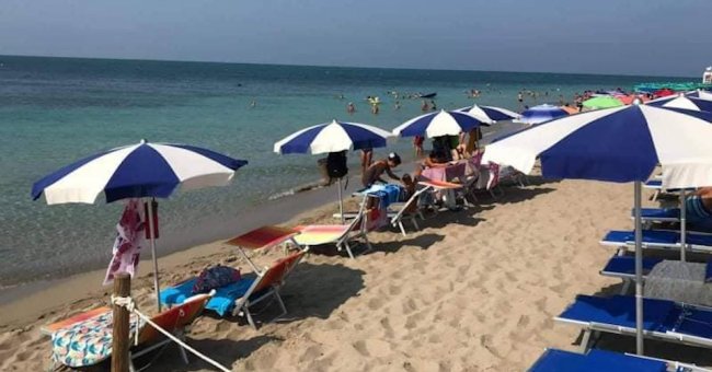 Lettini e ombrelloni bianchi e blu su una spiaggia.