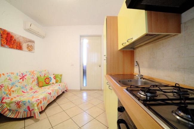 Cucina moderna con mobili gialli, divano colorato e condizionatore d'aria.