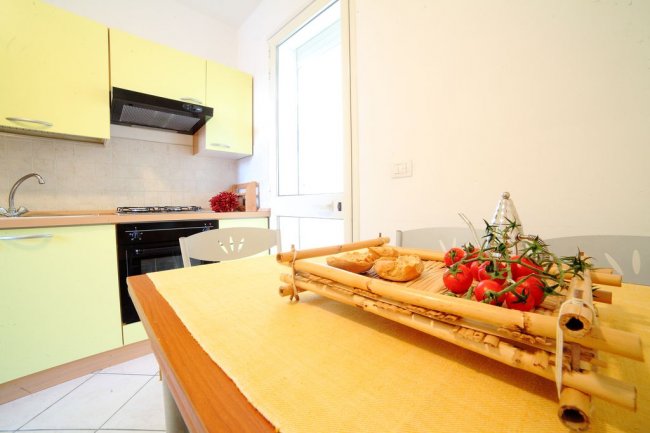 Tavolo da pranzo con tovaglia gialla, pomodori e pane in un vassoio di legno.