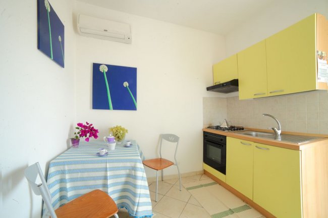 Una cucina compatta con armadietti gialli e un tavolo con tovaglia a righe blu.